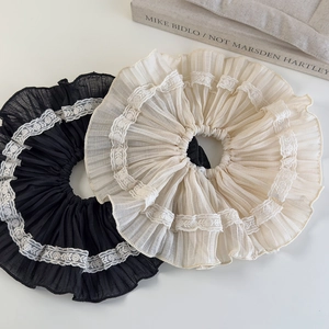 Close-up of elegant pleated lace scrunchies in black and beige on an artistic background