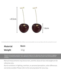 Close-up of red resin cherry earrings with golden hooks and glitter detail