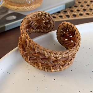 Détail d'un bracelet en rotin tressé à la main sur un plateau en céramique au style naturel