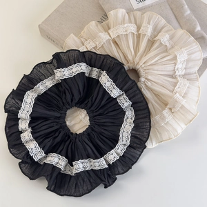 Close-up of black and beige lace scrunchies with intricate embroidery on soft fabric