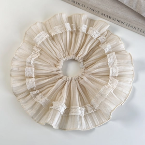 Close-up of beige ruffled hair scrunchie with lace trim on a minimalist white background