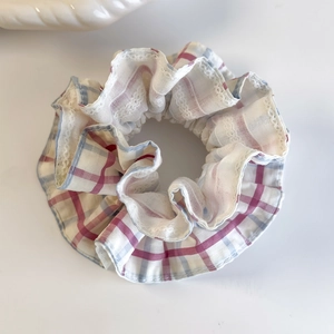 Close-up of pink and blue plaid scrunchie featuring delicate white lace trim details
