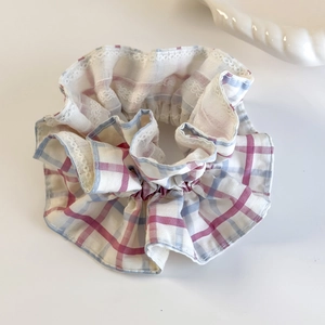 Detail of sweet plaid scrunchie with white lace edges in pink and blue tones