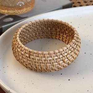 Gros plan d'un bracelet en rotin tressé à la main sur une assiette en céramique bohème