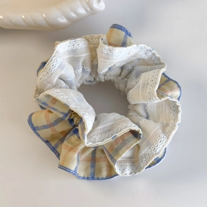 Detailed close-up of blue and orange checkered scrunchie with delicate white lace trim