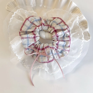Close-up of pink and blue plaid scrunchie with lace trim and bow in a shell tray