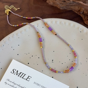 Gros plan sur un collier de perles fait main avec cristaux violets et fermoir doré