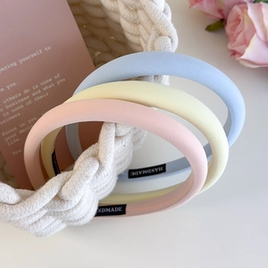 Detailed macro view of three pastel macaron sponge headbands with handmade woven labels