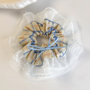 Detail of blue and yellow plaid scrunchie with scalloped white lace and a light blue bow