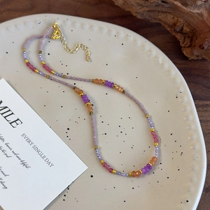 Vue détaillée du collier en perles violettes avec billes dorées et fermoir mousqueton