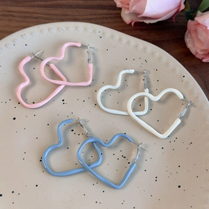 Detailed close-up of cream-colored heart hoop earrings in pink, white, and blue finishes