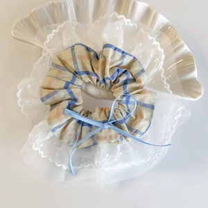 Close-up of a plaid hair scrunchie with white polka dot lace and a light blue bow tie