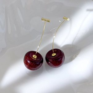 Detail of dark red cherry resin earrings with fine glitter and gold stems