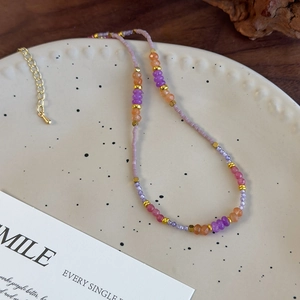 Collier fait main en perles violettes avec breloques en résine et accents dorés sur assiette