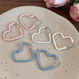 Three pairs of pastel cream heart-shaped hoop earrings in pink, white, and blue finishes
