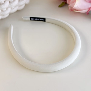 Close-up of handmade cream fabric headband featuring a satin finish and woven label