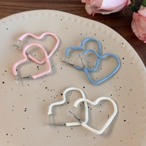 Detailed view of pastel enamel heart hoop earrings in pink, blue and white on ceramic tray
