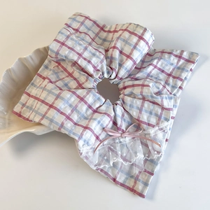 Pink and blue plaid scrunchie with white lace trim and bow in a shell tray