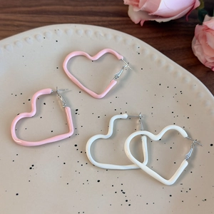 Detail of cream heart hoop earrings in pink and white enamel on a ceramic tray