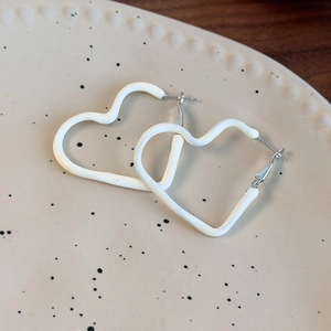 Detail of cream white heart earrings with wavy texture on a minimalist ceramic tray