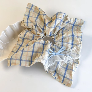 Detail of blue and yellow plaid scrunchie with white lace trim and blue ribbon bow