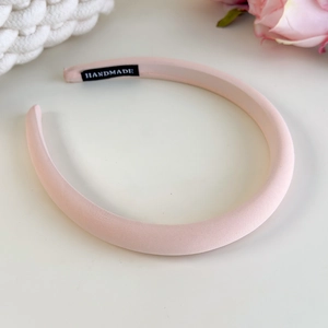 Detailed view of handmade pink padded fabric headband with stitched logo label