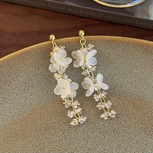 Macro detail of bohemian blue flower crystal tassel earrings on a ceramic dish