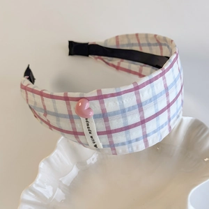 Close-up of pink and blue plaid headband with a small heart and handmade woven label