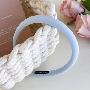 Detail of light blue handmade fabric headband with woven basket and rose background