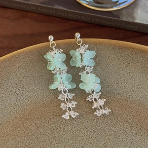 Detail of bohemian silver earrings with mint green flower charms and crystal beads