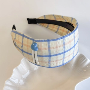 Detailed shot of yellow and blue plaid headband with a blue heart and handmade label