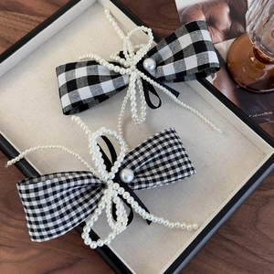 Detail view of houndstooth bow hair clips with elegant trailing pearl tassels