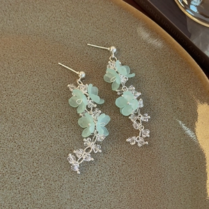 Close-up of bohemian blue flower earrings with long crystal tassels and green petals