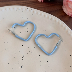 Detail view of light blue heart-shaped hoop earrings on a minimalist ceramic plate