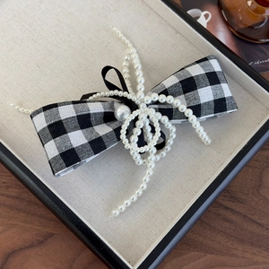 Close-up of elegant pearl tassels and houndstooth bow on a chic hair clip detail