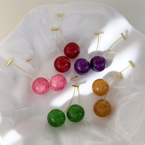 Sparkling resin cherry drop earrings in five colors displayed on a white ceramic tray