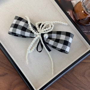 Detail of elegant houndstooth bow hair clip with pearl embellishment and trailing beads