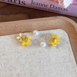 Dettaglio degli orecchini a fiore di osmanto giallo con perle su vassoio in legno