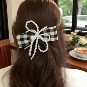 Elegant houndstooth bow hair clip with pearls shown on long hair from a back view