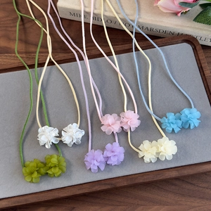 Gros plan de colliers ras-du-cou floraux colorés aux tons macaron sur un plateau en bois
