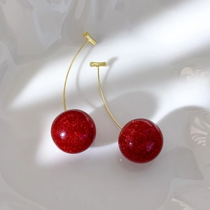 Detail of red cherry earrings with gold hardware and sparkling glitter finish