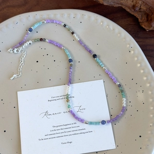Collier artisanal de perles colorées avec pierres en verre sur plateau céramique
