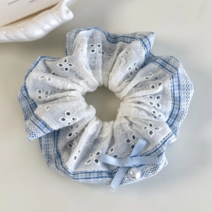 Detail of blue plaid hair scrunchie with white lace, ribbon bow and pearl bead decoration