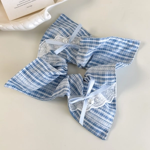 Detail of blue plaid fabric hair scrunchie with white lace edges and pearl bow accents