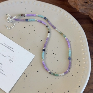 Collier de perles colorées avec pierres violettes et bleues sur une assiette