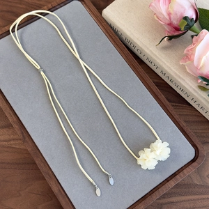 Vue détaillée de deux fleurs de camélia blanches sur cordon en daim beige doux