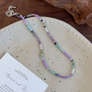 Détail du collier de perles fait main avec perles violettes et vertes sur platine