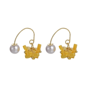 Dettaglio macro del gancio dorato con perla bianca e petali di resina gialla brillante