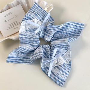 Detail of blue plaid fabric hair scrunchie with lace edges and faux pearl bow decor