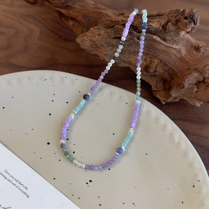 Détail de perles en résine colorées et pierres de cristal violettes sur bois et céramique
